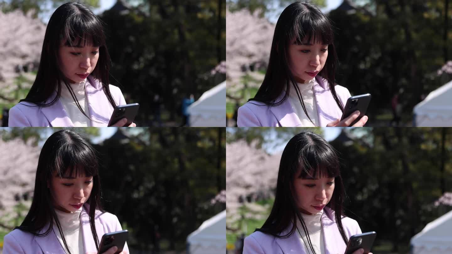 日本女子手持樱花手持智能手机的照片