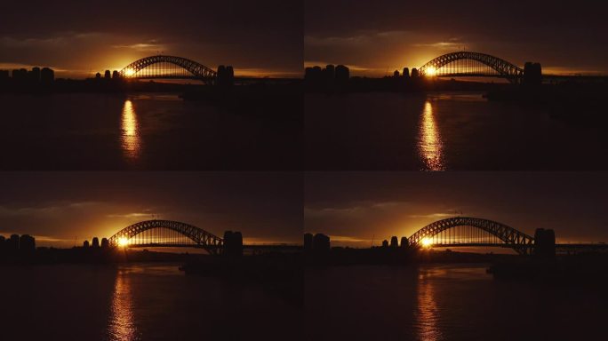 在金色的冬日日出中，宽镜头拍摄了悉尼海港大桥的背光剪影