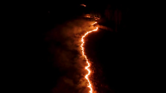 夜火在森林里有火和烟。史诗级的航拍视频，一团冒着烟的火焰。火:夜间燃烧的、发光的火森林火灾。干草在燃