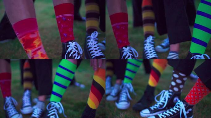慢镜头显示了草地上五颜六色的袜子和匡威运动鞋的腿