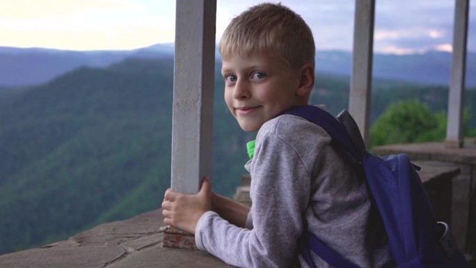 以山为背景的孩子。这个男孩在山里旅行。和孩子一起旅行。学生露营。山旅游。一次激动人心的旅行。学童的爱