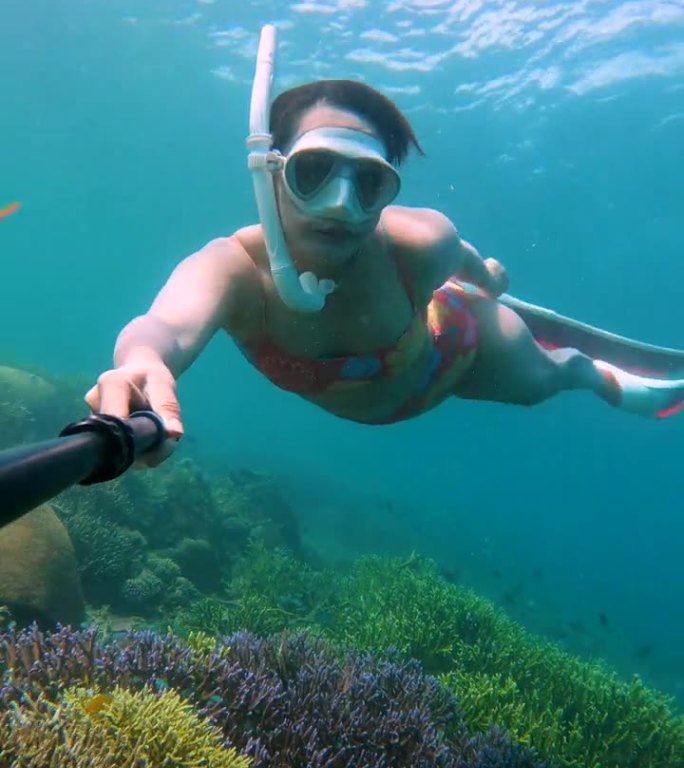 年轻女子自拍视频和在珊瑚礁周围潜水