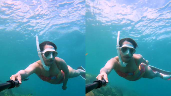 年轻女子自拍视频和在珊瑚礁周围潜水