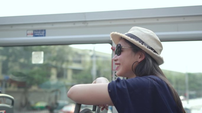 美丽的女孩在城市旅游巴士上玩得很开心，看着相机