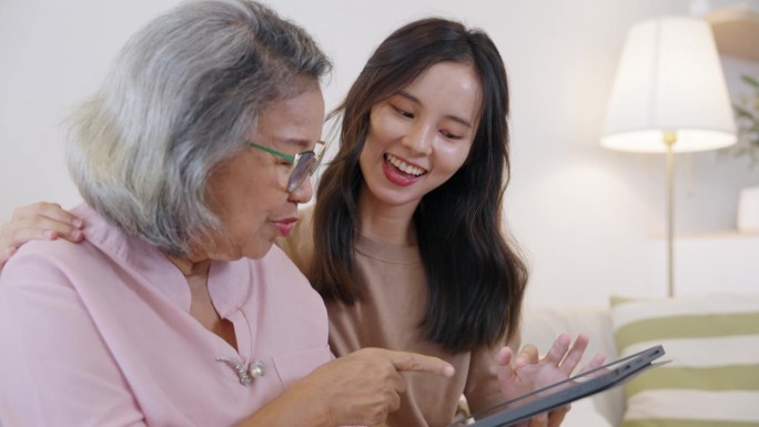 快乐的奶奶和孙女用数码平板电脑看搞笑视频