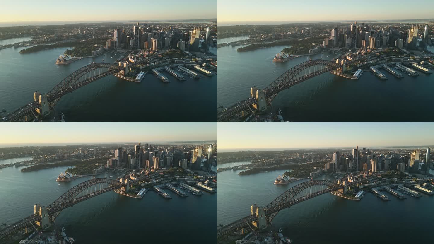 澳大利亚新南威尔士州悉尼日出时，悉尼港大桥、各种办公大楼和歌剧院上空的4K鸟瞰图