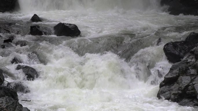 瀑布后的慢动作，有泡沫的河水在狭窄的岩石和多石的山谷中流动