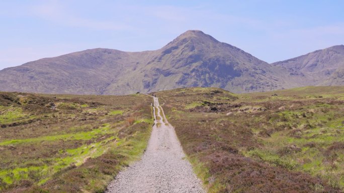 在一个阳光明媚的春日里，沿着西高地路的步道延伸到苏格兰高地的远处