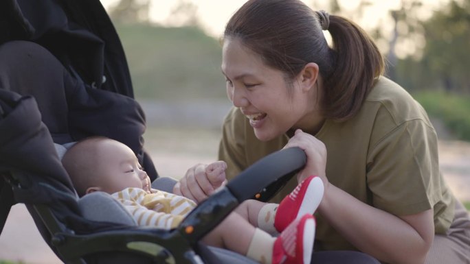 母亲在公园里放松，她的孩子坐在婴儿车上