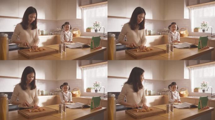 一个韩国女人和她的女儿在家里的厨房里的肖像:美丽的母亲准备做午餐，同时与她旁边的可爱的孩子交谈。幸福