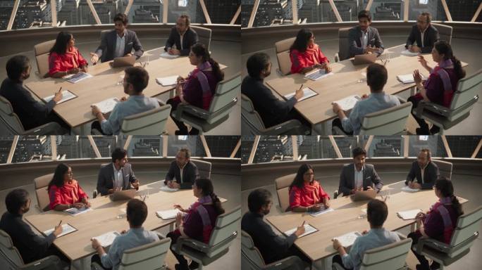 高角度镜头的不同团队的专业南亚商人会议在办公室会议室。创意团队坐在桌子后面，讨论社交媒体营销策略