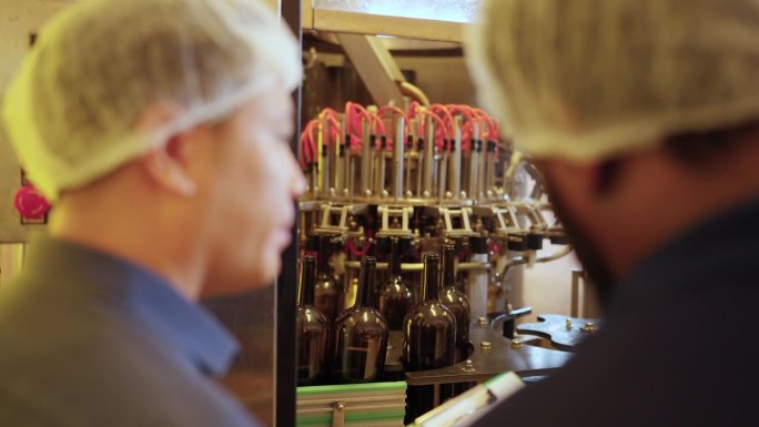 4K白酒厂工人在生产线上检查白酒洗瓶机。