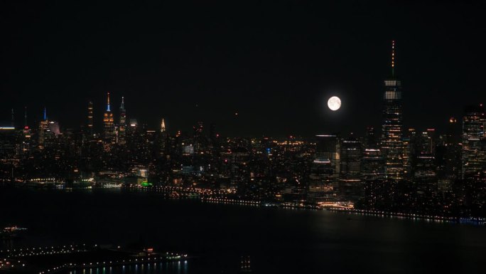 纽约曼哈顿建筑和满月的空中夜景。全景金融区镜头从直升机。城市景观与办公大楼和摩天大楼