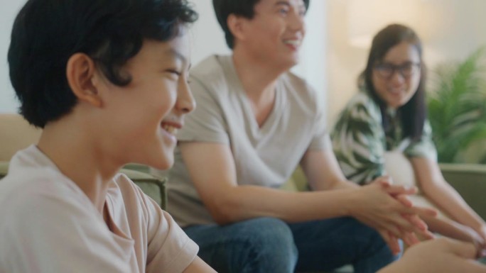 亚洲家庭看电视，男孩浏览智能电视应用，家庭休闲时光。