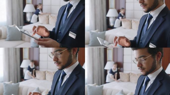 客房服务员整理床铺时，酒店管理员在平板电脑上查看信息