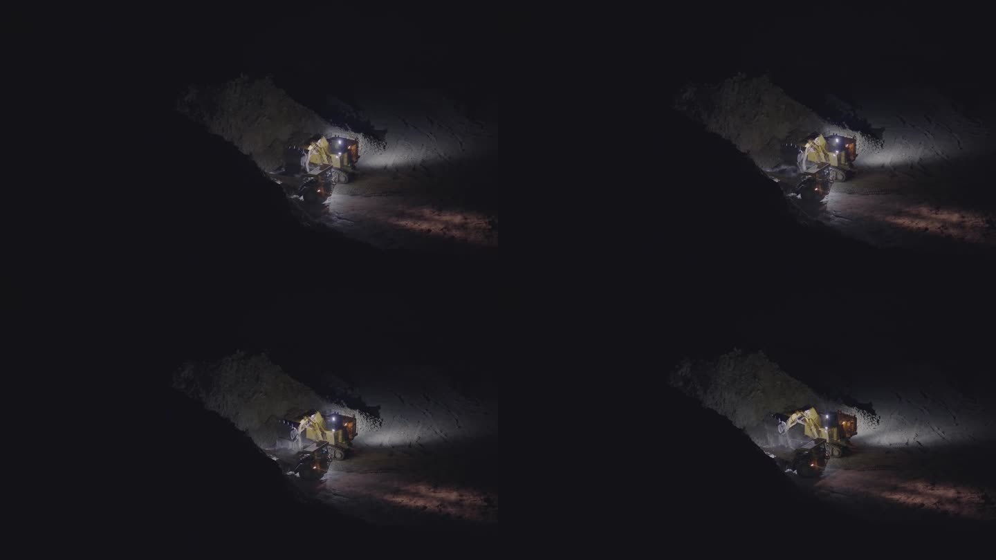 夜间在露天矿坑作业的挖掘机。画面中，挖掘机翻动着装有矿石的黄色铲斗进入自卸车，慢动作