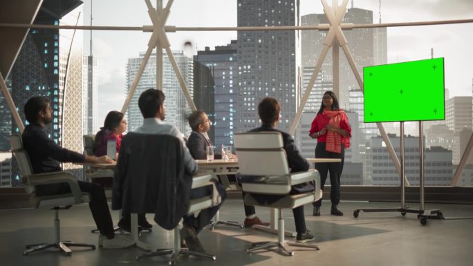 南亚女商人向一群印度投资者展示数据。电视屏幕与绿屏模拟显示。现代办公会议室商务会议演示