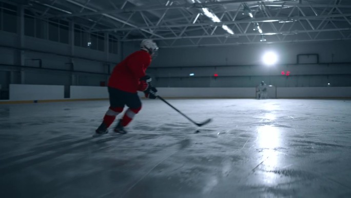 一名职业冰球运动员在有电影般灯光的赛场上熟练地用冰球棒击球并进球的广角镜头