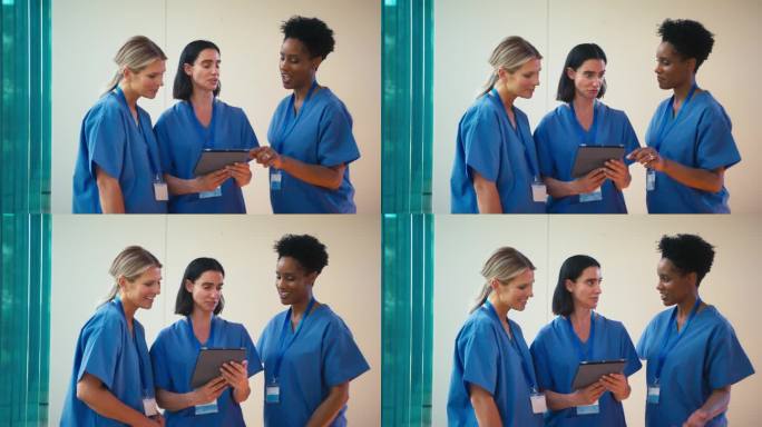 三个成熟的女医生穿着手术服拿着电子平板电脑在医院讨论病人的记录