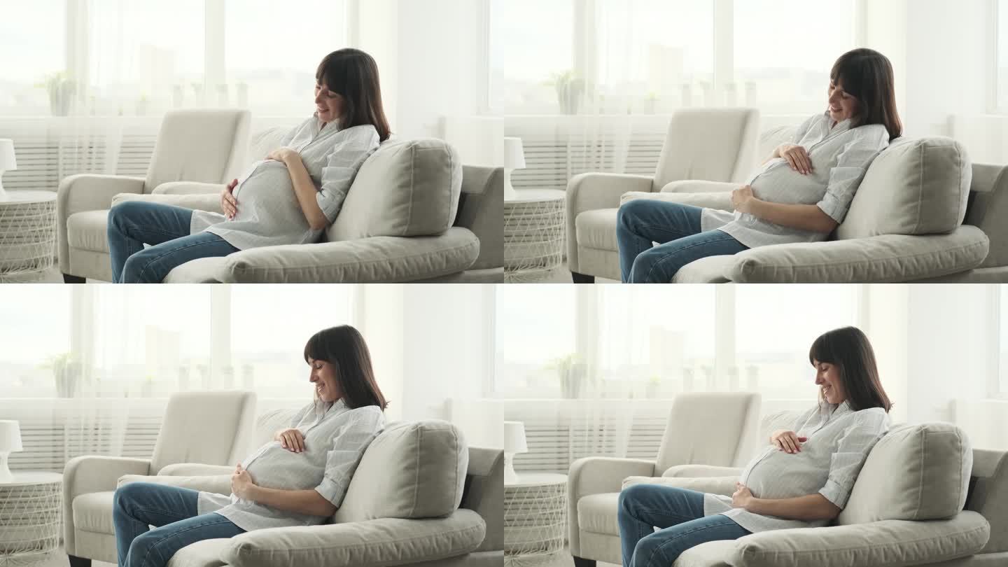 可爱的孕妇在沙发上揉肚子
