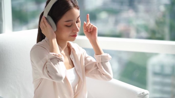 亚洲女商人戴着耳机听音乐跳舞的肖像