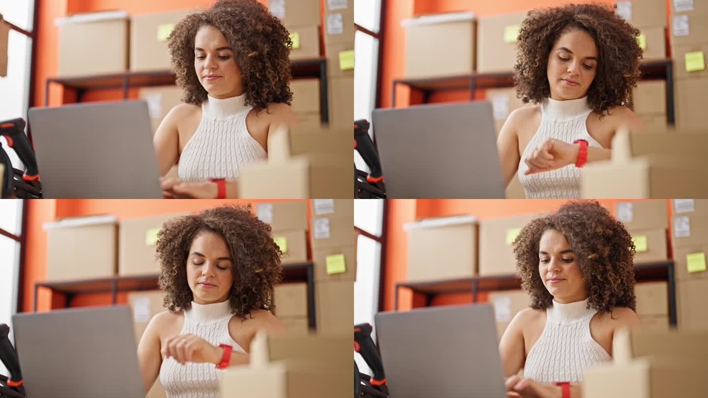 年轻美丽的西班牙裔女性电子商务商务工作者使用笔记本电脑在办公室看手表