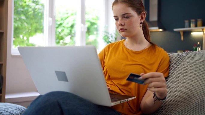 一个十几岁的白人女孩在家里用笔记本电脑上网购物