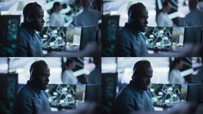 非洲专家在一个黑暗的高科技监控室，专注于电话和计算机工作。黑色技术支持经理使用内置麦克风的耳机与客户