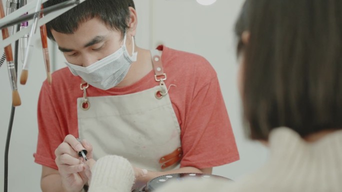 亚洲男性美容技师在美甲沙龙提供美甲服务