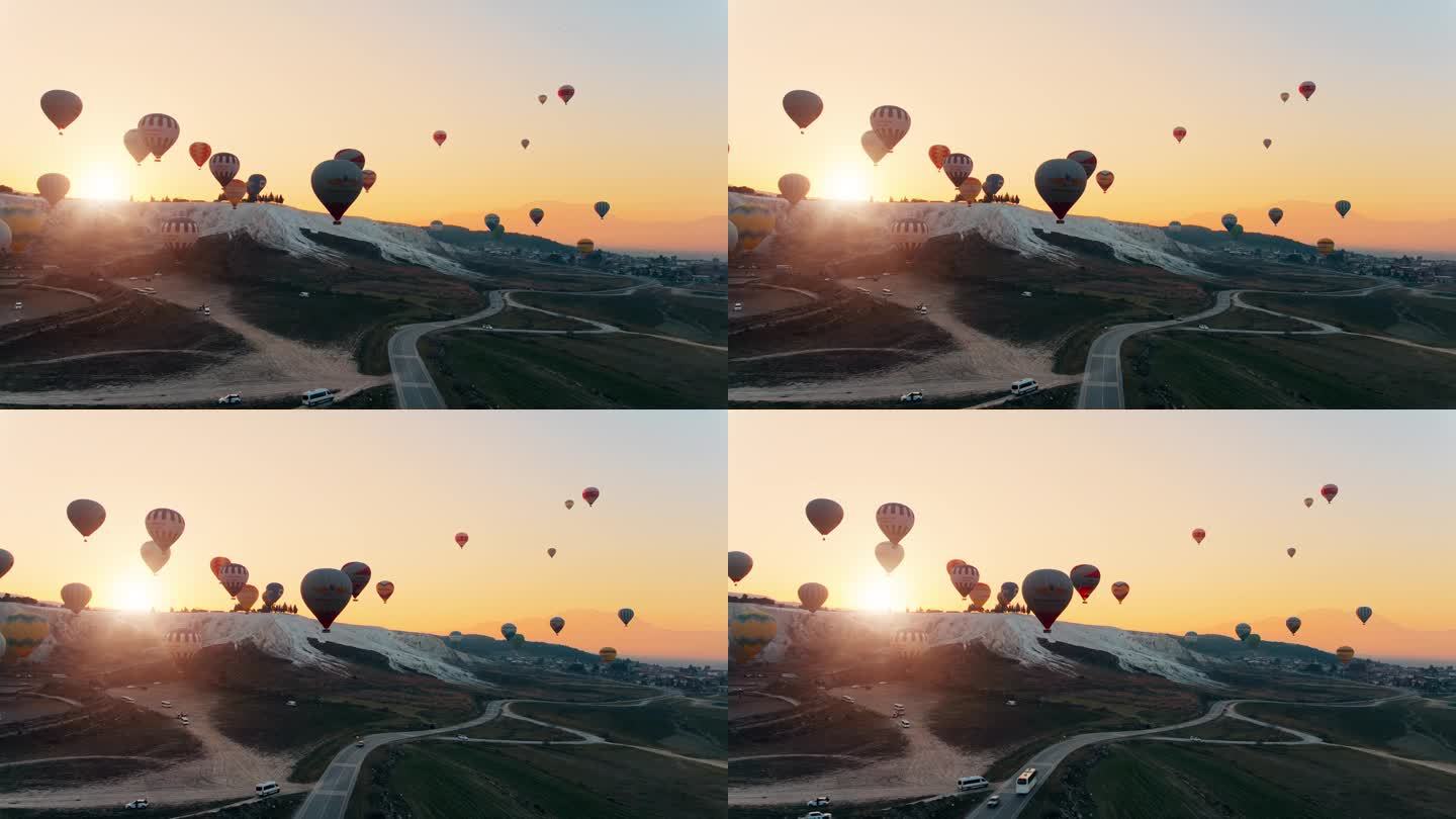 热气球飞过Pamukkale山谷，映衬着群山和忧郁的天空。航拍无人机视频