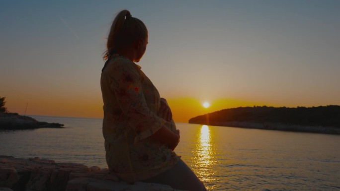 孕妇摸着肚子望着大海的侧视图