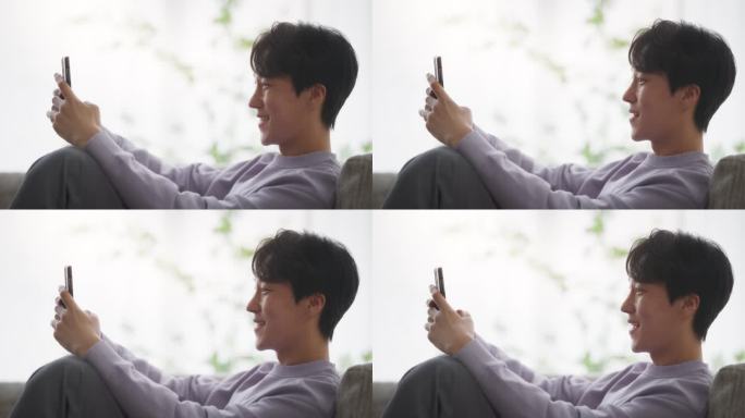 韩国年轻人一边放松一边玩智能手机享受闲暇时光。亚洲男性使用生产力应用程序、社交媒体网络和个人发展工具