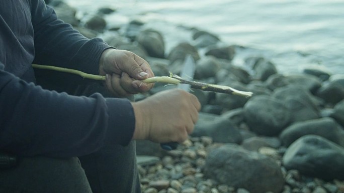 一个人在湖边的篝火旁计划着一根木棍