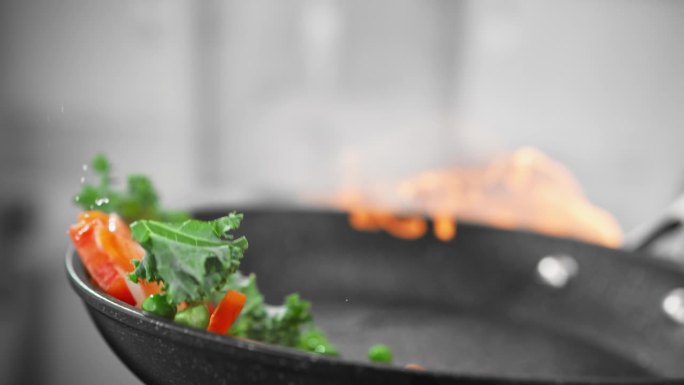 在慢动作的火焰上炒菜时，用煎锅炒虾和蔬菜