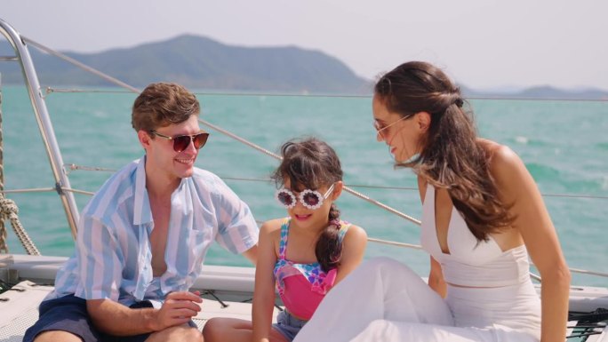 高加索幸福的一家人坐在游艇甲板上，而游艇在户外。年轻漂亮的夫妇在双体船航行的时候一起出去玩，和女儿一
