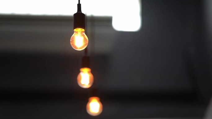 悬挂在天花板上的灯泡闪烁的灯光装饰了咖啡馆的暖橙色。