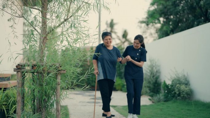 积极的生活方式和老年护理:帮助老年妇女拄着拐杖走路|家庭保健