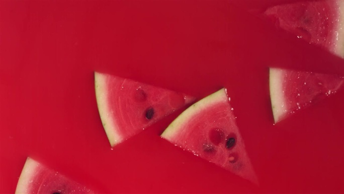 新鲜西瓜片落入红色果汁漩涡的超级慢动作镜头