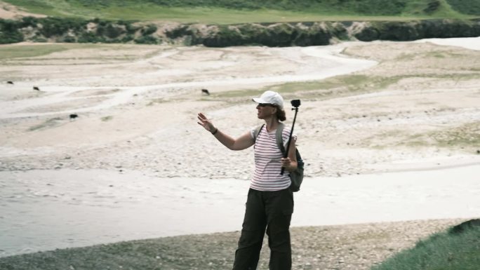 一位兴高采烈的女游客正在用视频记录她在Saryjaz河谷的旅行