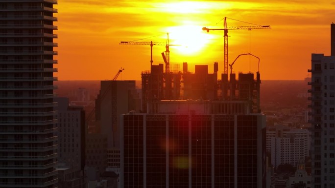 夕阳下美国市区住宅开发新工地。佛罗里达州迈阿密的工业塔式起重机。美国住房增长的概念