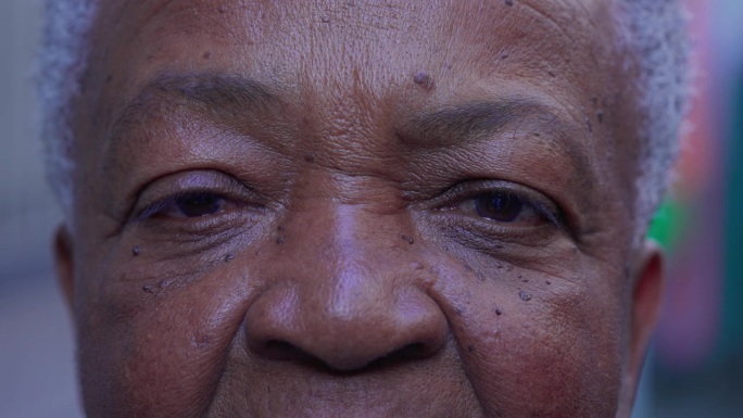 微距特写，一位上了年纪的黑人妇女满脸皱纹，神情疲惫。一位资深的非裔美国女士