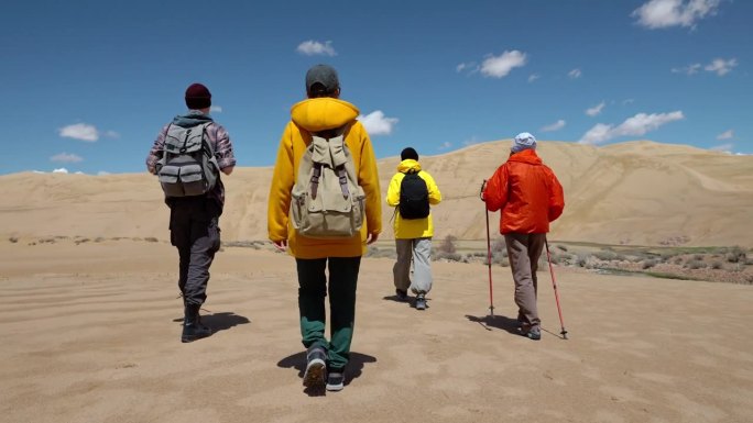 一组四名旅行者一起沿着荒野地区向前走沙漠