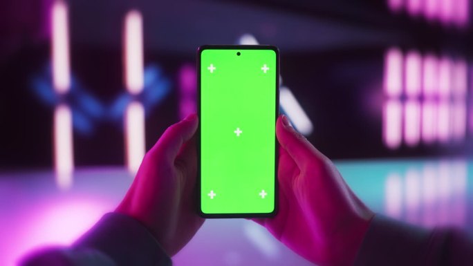 在未来的霓虹灯房间里，用绿屏Chromakey模拟显示器在智能手机上滚动应用程序。视频模板与孤立的数