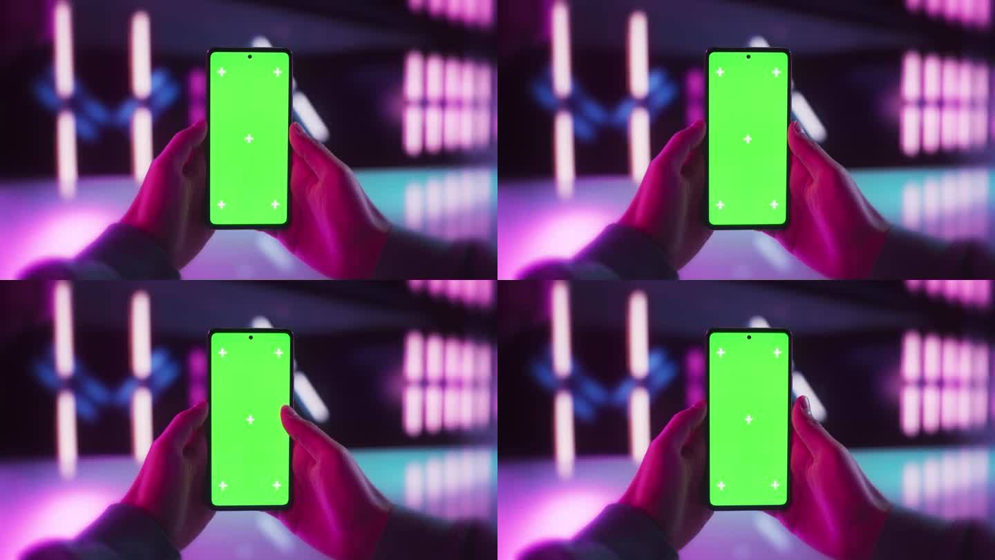 在未来的霓虹灯房间里，用绿屏Chromakey模拟显示器在智能手机上滚动应用程序。视频模板与孤立的数