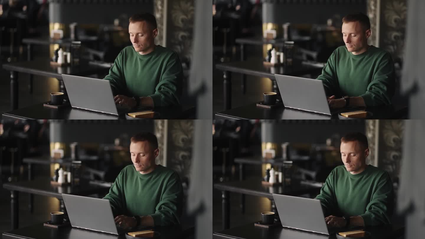 黑客或程序员在网上用笔记本电脑工作，男人独自坐在咖啡馆的桌子旁