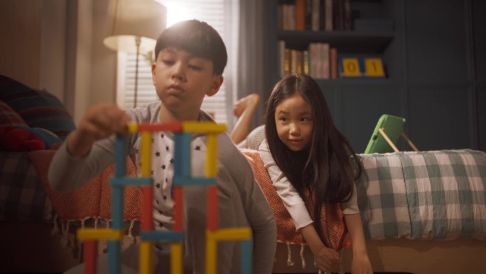 小男孩在儿童房玩积木，他聪明的小妹妹在玩数码平板电脑。快乐的韩国孩子创造性地度过时间
