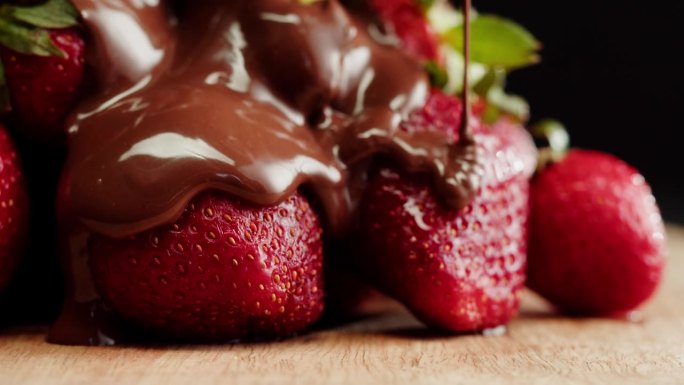 融化巧克力中的草莓特写，融化巧克力棒做火锅。浆果配巧克力慕斯。专业厨师烹饪蛋糕甜点。