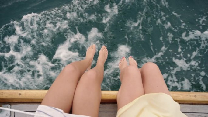 头顶女友的腿挂在海上的帆船上奢侈的生活方式快乐的冒险旅行度假