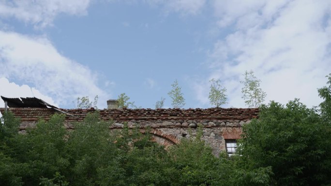红色砖墙的旧建筑废墟与倒塌的屋顶对着蓝天。