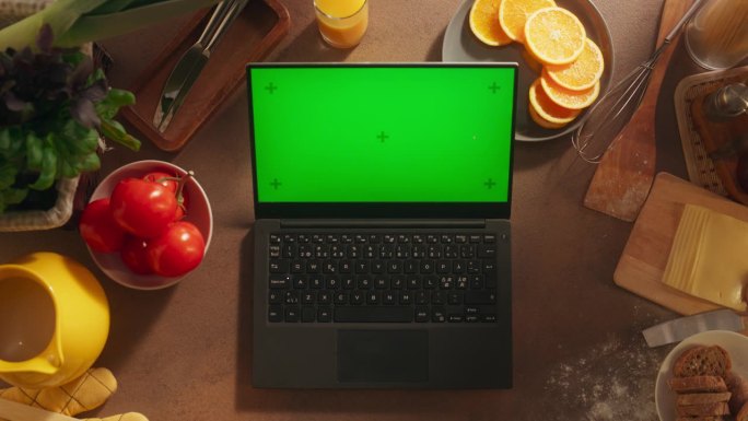 一台笔记本电脑的顶部静态视图与模拟绿屏Chromakey显示器站在一个健康的早餐厨房的桌子上，充满了